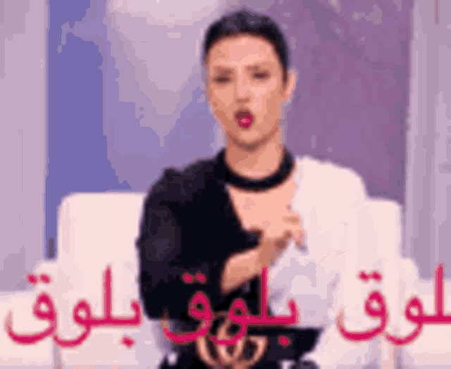a woman is sitting on a couch with arabic writing behind her .