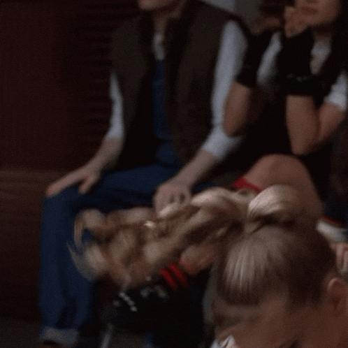 a cheerleader is smiling while sitting in a crowd of people