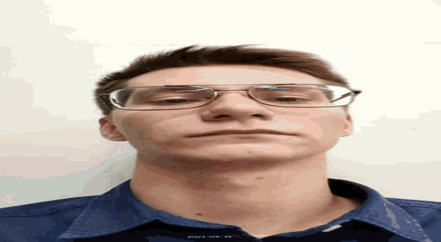 a man wearing glasses and a blue shirt with the year 2021 on the neck