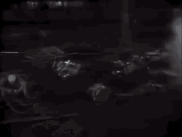 a group of people are standing in a dark room with smoke coming out of it