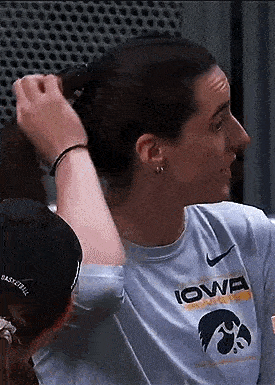 a woman in a nike shirt is tying her hair in a bun .