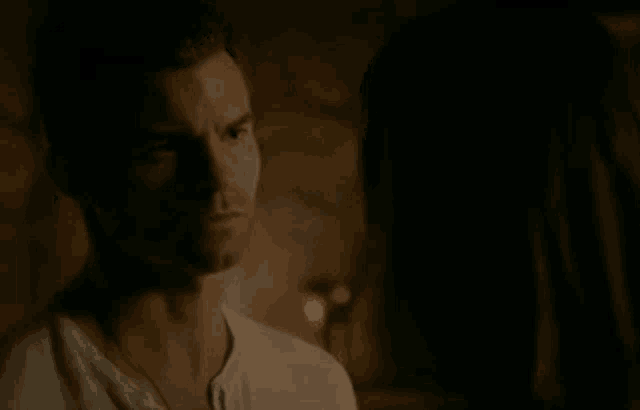 a man and woman are looking at each other in the dark .