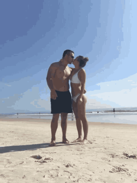 a man and woman are kissing on the beach