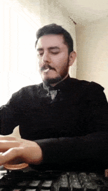a man with a beard is smoking while typing on a keyboard
