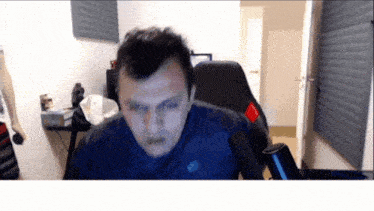 a man in a blue shirt is sitting in front of a computer screen