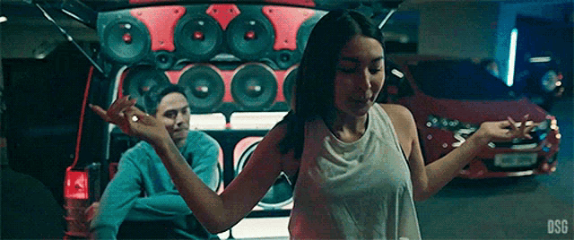 a woman is dancing in front of a man in a wheelchair in a parking garage .