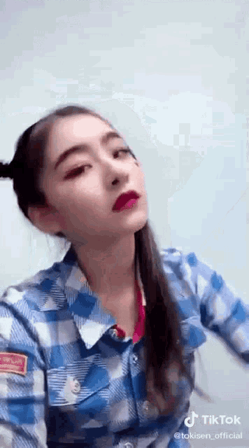 a girl in a plaid shirt is making a funny face .