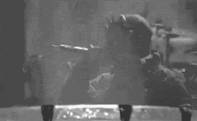 a black and white photo of a man holding a gun in a foggy room .