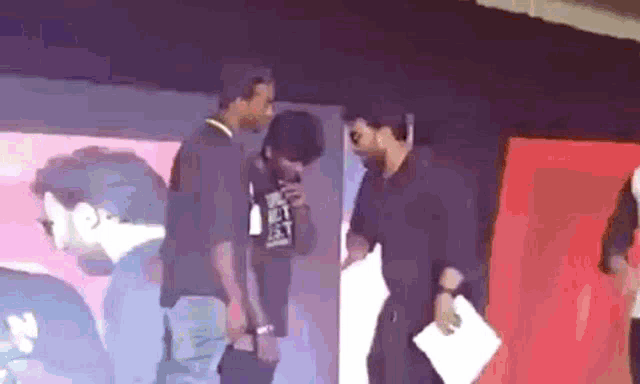 a man wearing a t-shirt that says ' i love you ' on it talks to another man on a stage