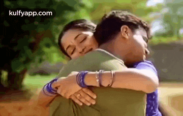 a man and a woman hugging each other in a park .