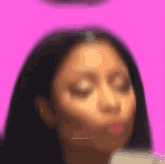 a blurry picture of a woman making a funny face on a pink background .
