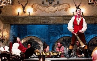 a man in a red vest is standing in front of a group of people and asking is that fair