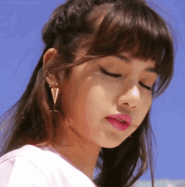 a close up of a woman 's face with her eyes closed wearing earrings and pink lipstick .