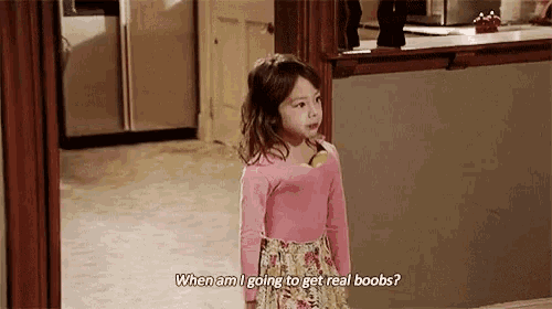 a little girl is standing in a kitchen and asking when am i going to get real boobs ?