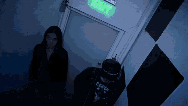 two people standing in front of a door that says exit