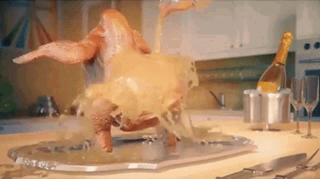 a turkey is on a tray with a bottle of champagne in the background .