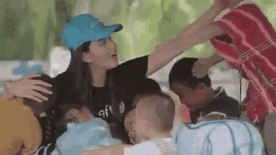 a woman in a blue hat is standing in a crowd of people .