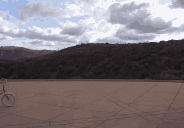 a bicycle is parked on a concrete surface in front of a mountain