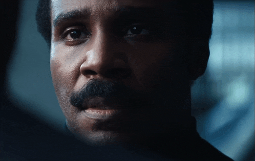 a close up of a man 's face with a mustache in a dark room