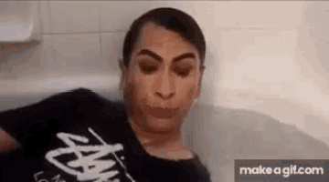 a woman is sitting in a bathtub with her mouth open and making a funny face .