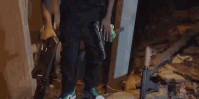 a man in a black shirt is holding a gun and a green toy gun .