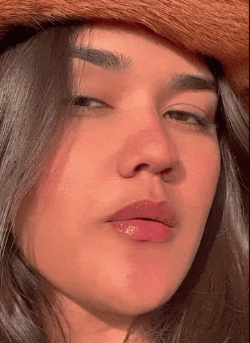 a woman wearing a cowboy hat looks at the camera