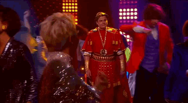 a group of people are dancing in a club while a man in a roman costume is standing in the middle of the crowd .