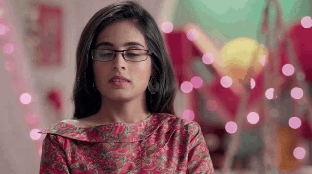 a woman wearing glasses and a pink shirt is looking down