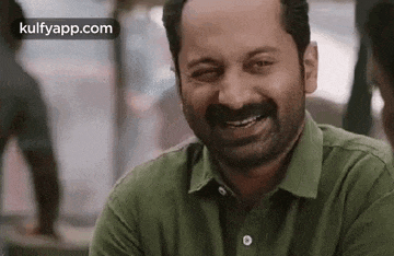 a man with a beard and mustache is smiling and looking at the camera .