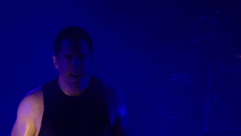 a man is singing into a microphone with a blue background