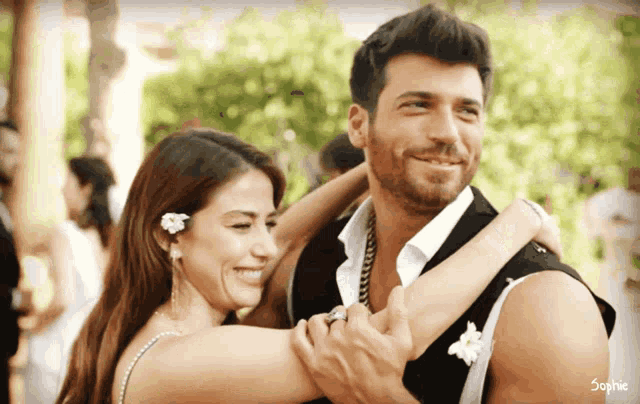 a man and a woman are hugging and smiling in front of a sign that says sophie on it