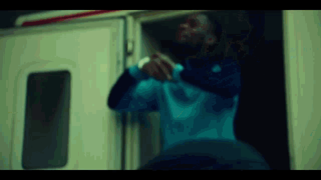 a man in a blue shirt is standing in front of a door .