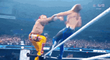 two men are wrestling in a ring and one of them is wearing a yellow outfit .