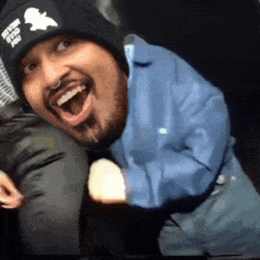 a man wearing a black beanie with a sherlock holmes logo on it is smiling