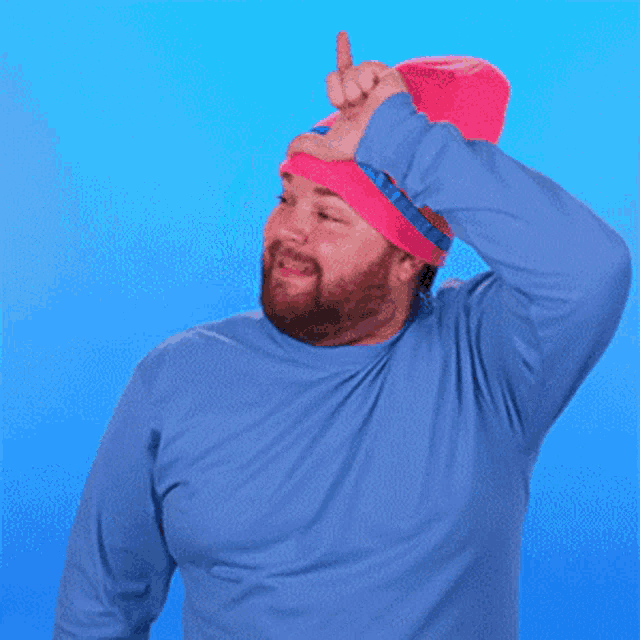 a man wearing a blue shirt and a pink hat is pointing his finger