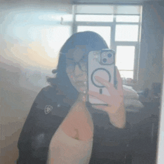 a woman is taking a selfie in front of a mirror with her cell phone .
