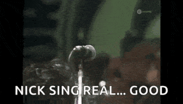 a woman is singing into a microphone with the words `` nick sing real ... good '' behind her .