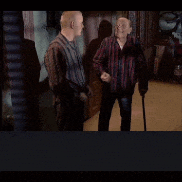 a bald man in a striped shirt is talking to someone in a foreign language