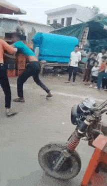 a group of people are fighting on the side of a street .