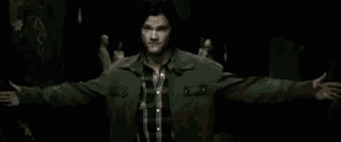 a man is standing in a dark room with his arms outstretched and says `` i love you this much '' .