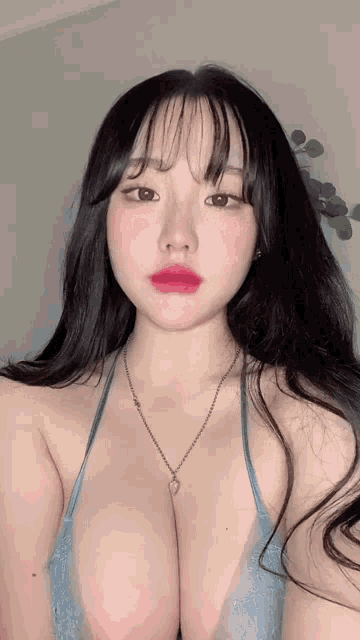a woman with long black hair is wearing a blue bra and necklace .
