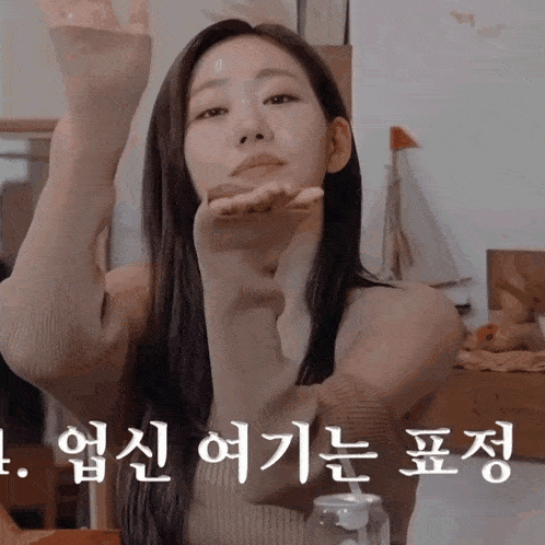 a woman blowing a kiss with korean writing on the bottom right