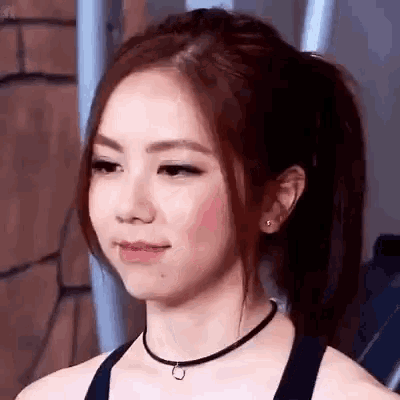 a woman wearing a choker and a ponytail is looking at the camera .