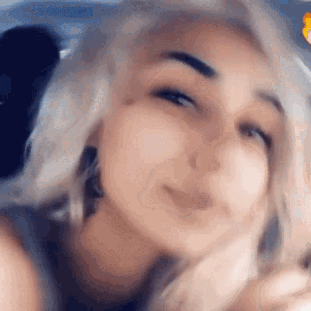 a close up of a woman 's face with blonde hair and a blurred background .