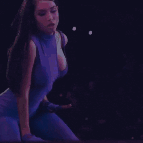 a woman in a blue dress is kneeling on a stage .
