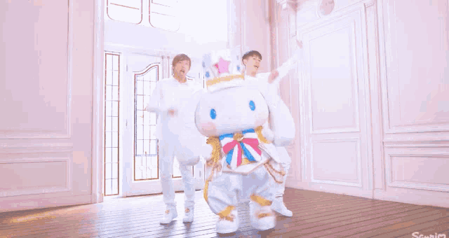 a group of people are dancing in a room with a stuffed animal that looks like cinnamoroll