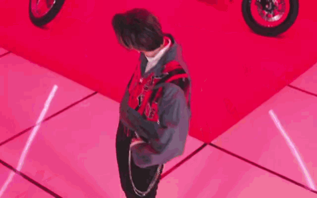 a young man is standing in front of two motorcycles on a red surface .