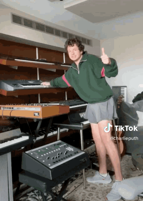 a man in shorts giving a thumbs up in front of a piano