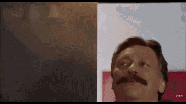 a man with a mustache is standing in front of a red ctc logo