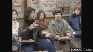 a group of people are sitting in a classroom and talking to each other .